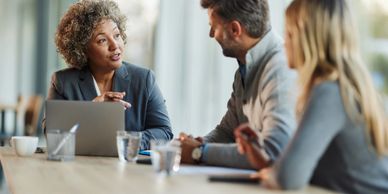 Business meeting with a woman speaking to two colleagues.
