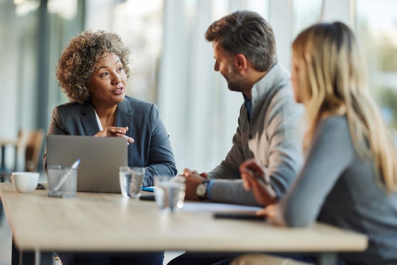 Mature female agent communicating with a couple during a meeting in the office.