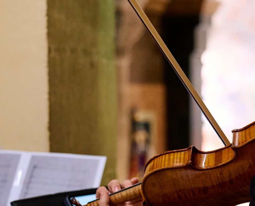 Close-up of a violinist playing with sheet music in the background.