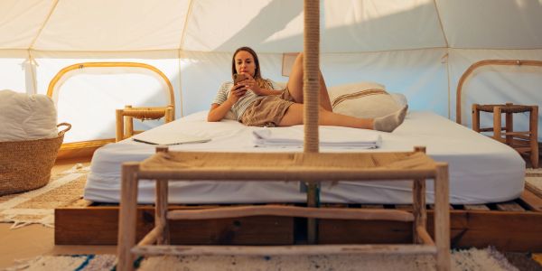 Woman relaxing on a bed inside a tent.