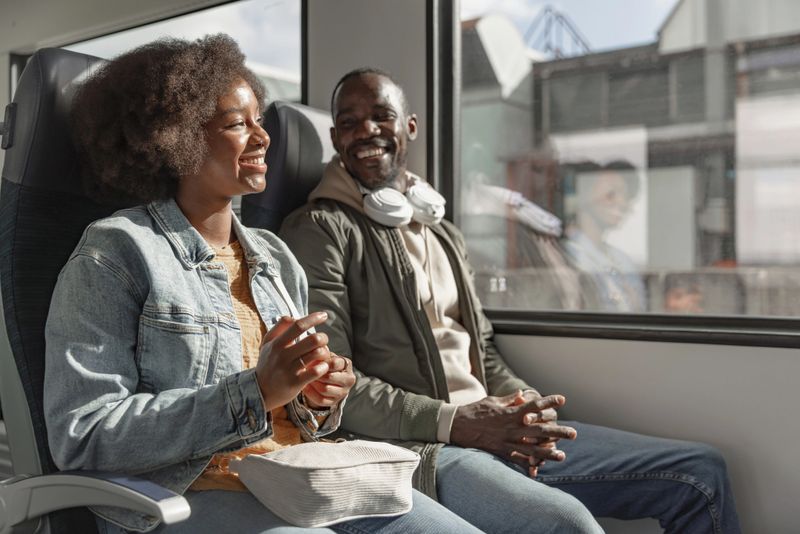 Passengers, a young African American woman, and a man having a friendly conversation during a train travel around Europe.