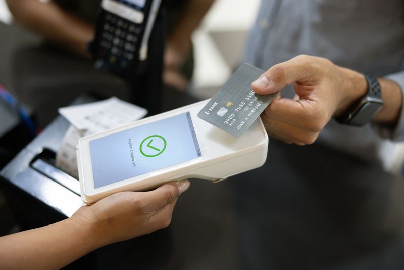 Close-up on a customer making a contactless payment with a credit card while buying tickets at the cinema