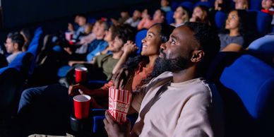 People enjoying a movie in a theater with popcorn and drinks.