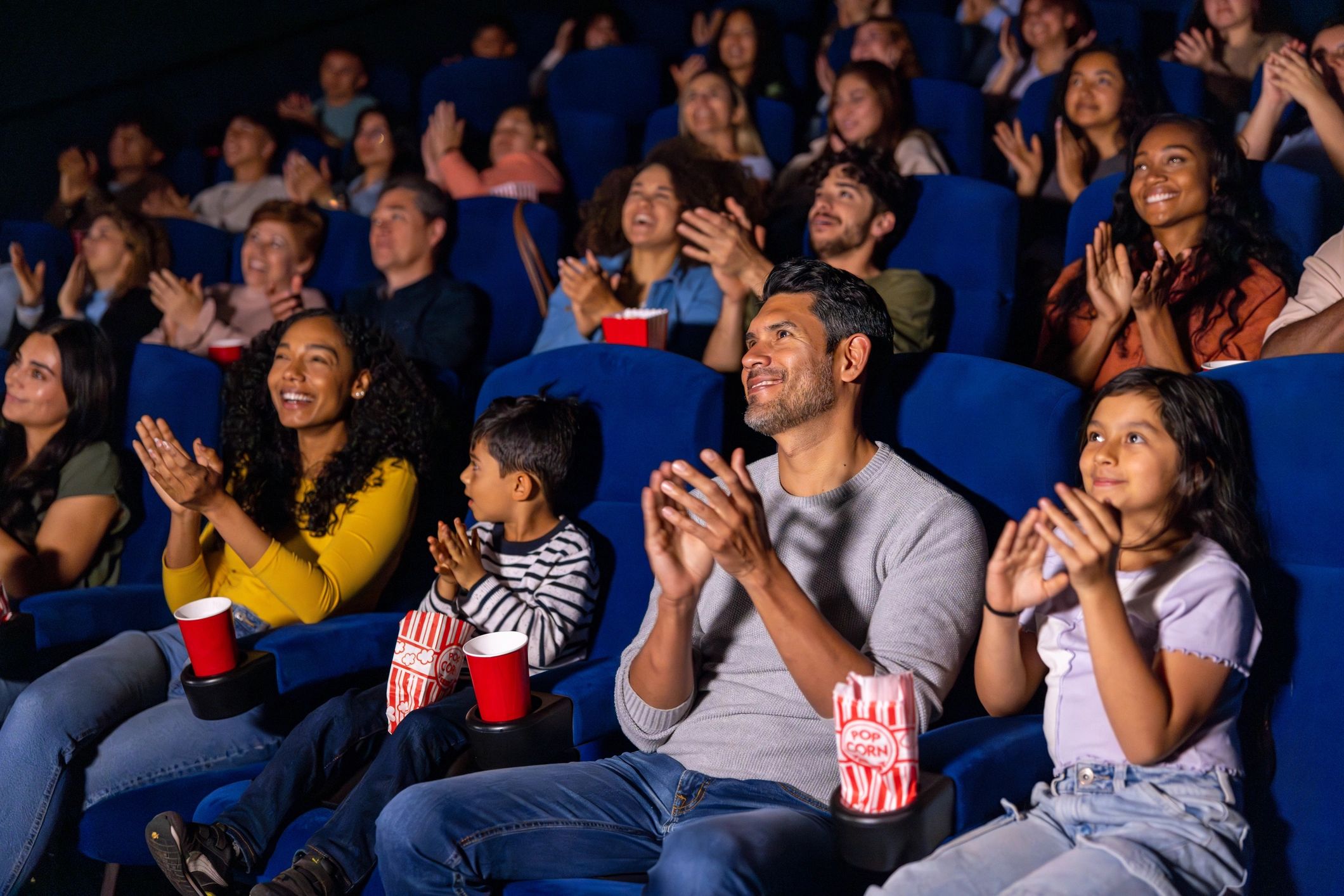 Audience clapping and enjoying a movie in a theater.