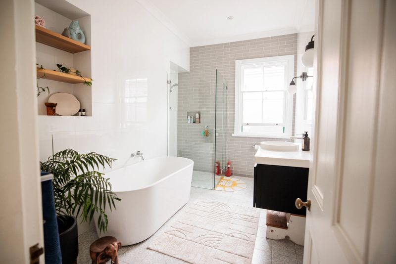 Contemporary bathroom showcases a sleek design with a freestanding tub, a glass shower, and abundant natural light, enhanced by the addition of natural greenery.