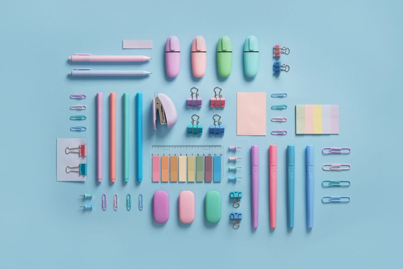 Pastel-colored stationery neatly arranged on a light blue background. Workplace organization. Back to school concept.
