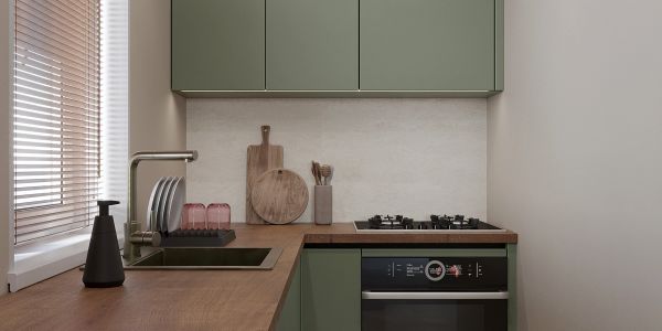 Modern kitchen with green cabinets and wooden countertop.