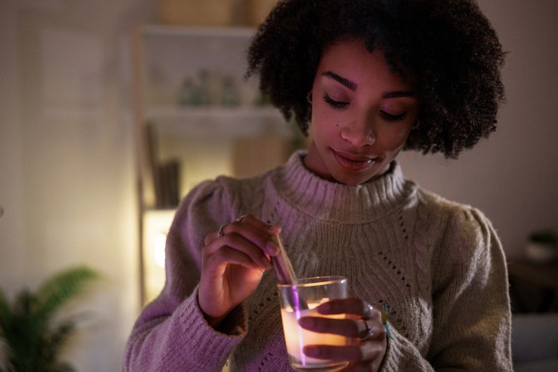 Serene young woman lighting a candle, creating a warm ambiance in her cozy home