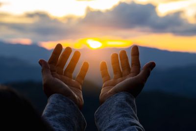 Hands reaching towards the sunset.