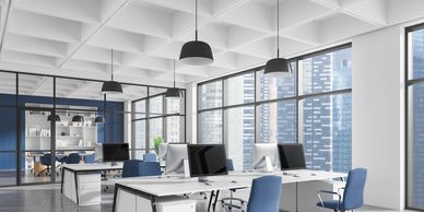 Modern office space with blue chairs and large windows overlooking city buildings.