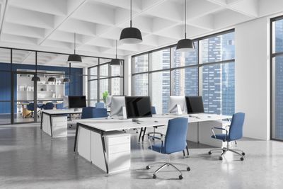 Modern open office with blue chairs and large windows showing cityscape. Office Cleaning