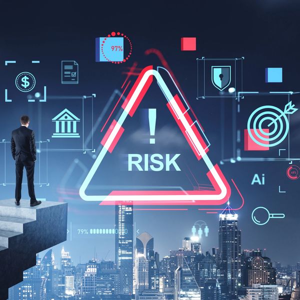 Businessman faces digital risk warnings over city skyline at night.