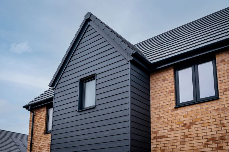 Generic new build home in England, with grey weatherboard cladding and brown brick