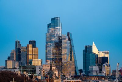 Modern skyscrapers in a city skyline at dusk with clear blue sky.