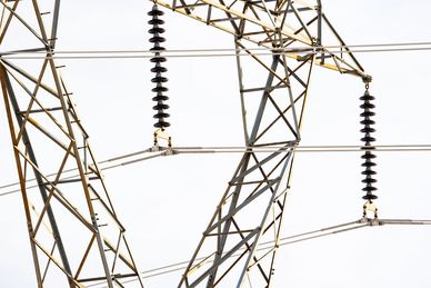 Close-up of electrical transmission tower with insulators and cables.