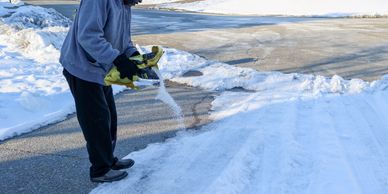 Person spreading salt on icy driveway.