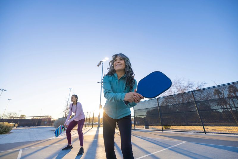 Women playing pickleball in the morning at the park.