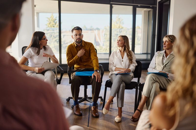 Young male entrepreneur talking about his problems during a group therapy in the office.