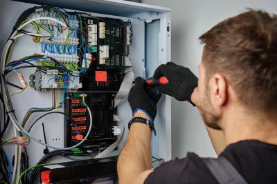 Man fixing electrical panel with screwdriver.