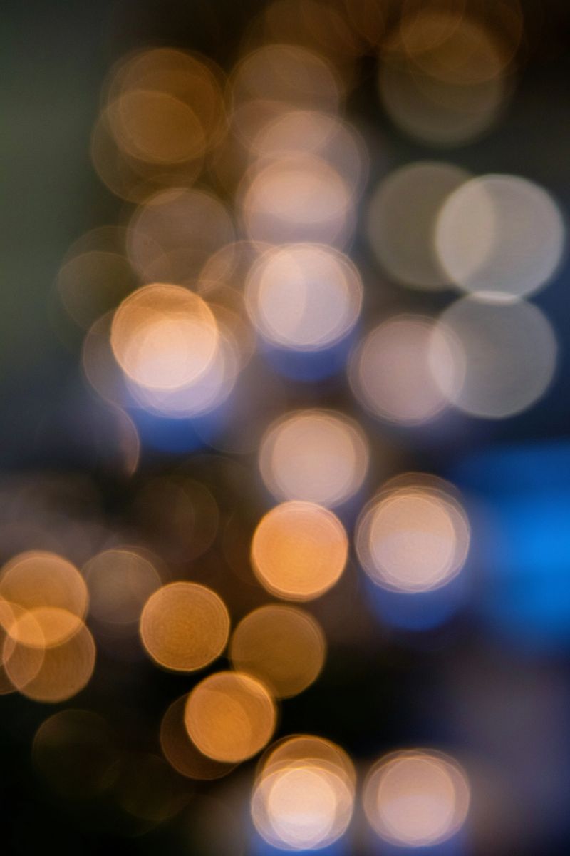 Blurred yellow bokeh light on blue background. Abstract defocused blinking holiday lights. Christmas and New Year sales template.