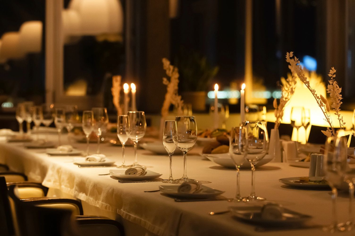 Elegant dining table set with candles and wine glasses for a formal dinner.