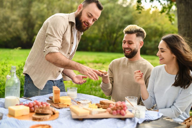 Joyful Male and Female Excited to Try Friend's Homemade Sandwiches on Picnic Party
