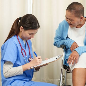 Nurse taking notes while talking to elderly woman in wheelchair.