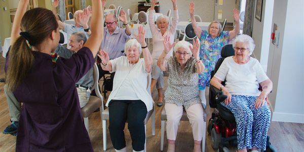 Seniors participating in a seated exercise session led by an instructor.