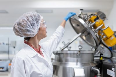 Scientist in protective gear operating industrial equipment in a lab.