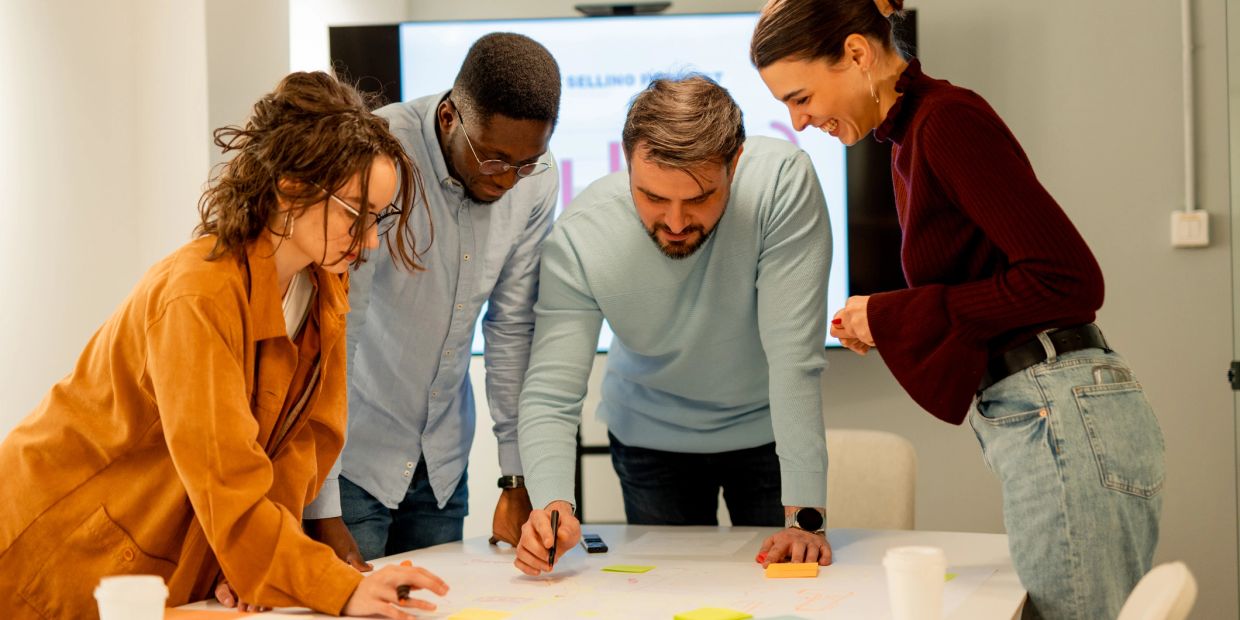 Four colleagues collaborate over documents in a modern office.