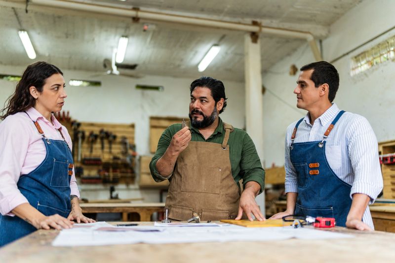 Mature carpenter man talking to coworkers at carpentry
