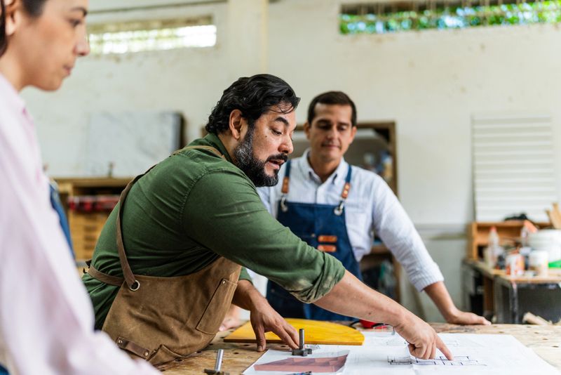Mature carpenter man talking to coworkers at carpentry