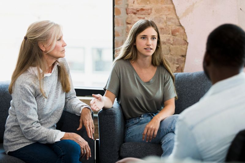 Mature women and young adult discussing mental health in a group therapy setting.