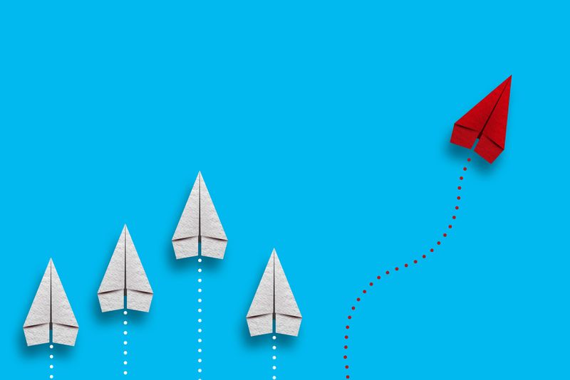 Leadership or different concept with red and white paper airplane path and route line on blue background.