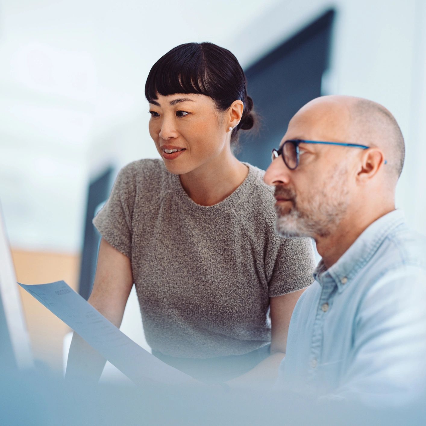 Two colleagues collaborating and reviewing a document at a computer.