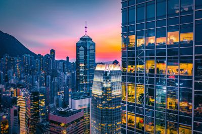 Colorful sunset over a bustling cityscape with illuminated skyscrapers.
