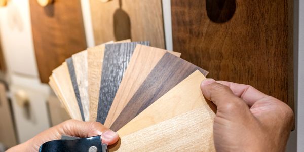 Person holding wooden laminate samples in various shades.