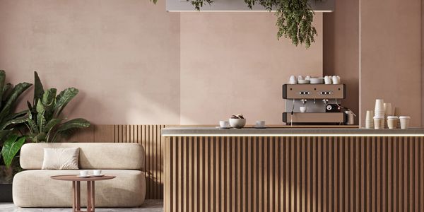 Modern coffee counter with sofa and plants.