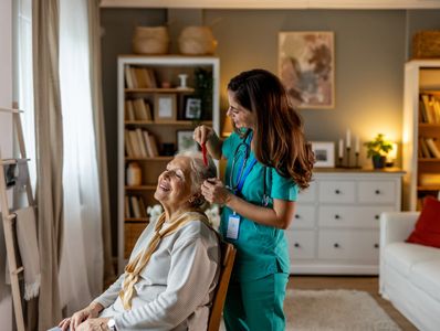 Nurse fixing elderly woman's hair in a cozy living room.