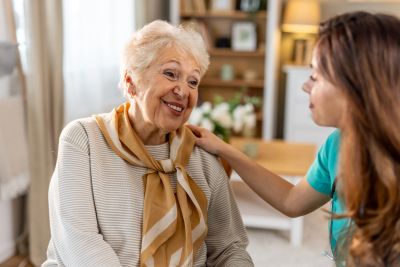 Young woman comforting elderly lady with a hand on her shoulder.