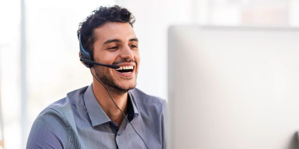 Man wearing headset and smiling while working on a computer.