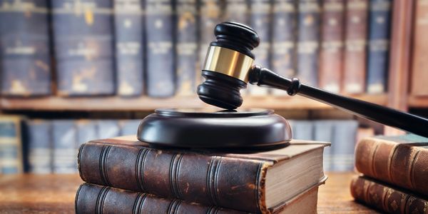 Judge's gavel resting on old legal books in a law library.