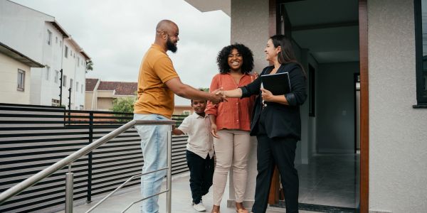 Real estate agent shaking hands with a family outside their new home.