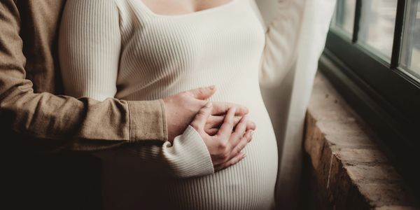 A pregnant woman and her partner resting their hands on her bump