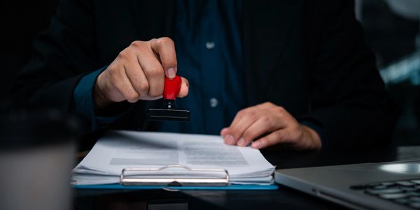 Person in formal attire filling out official documents with a pen.