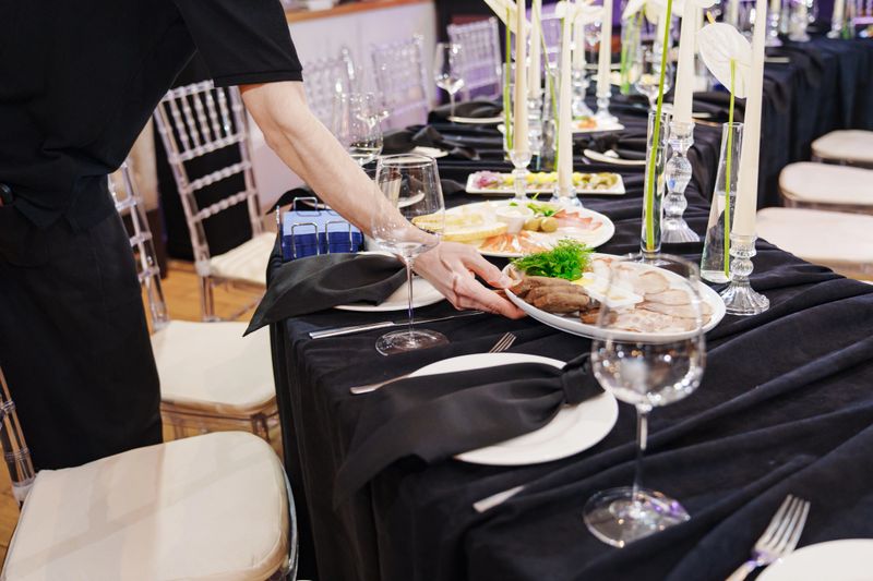Festive banquet table setting with classic white dishes and dark textiles. Festive dinner decor.