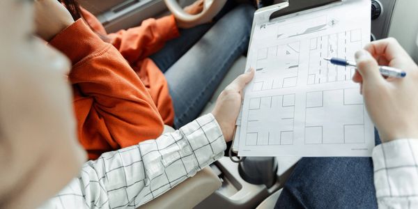 Person holding driving test paper in car.