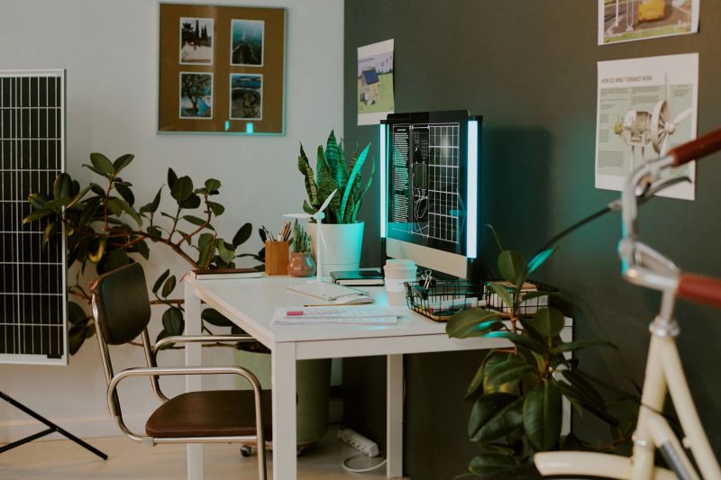 Modern office setup featuring solar panel analysis with tech gadgets and green plants. Demonstrating environmentally conscious work environment with various tools and equipment