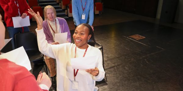Woman enthusiastically raising hand during a group meeting or workshop.