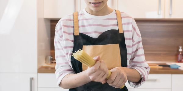 Person preparing to cook pasta in a modern kitchen.